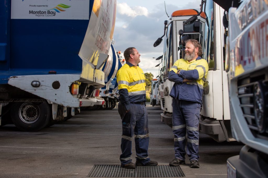 Cleanaway workers standing next to Cleanaway trucks